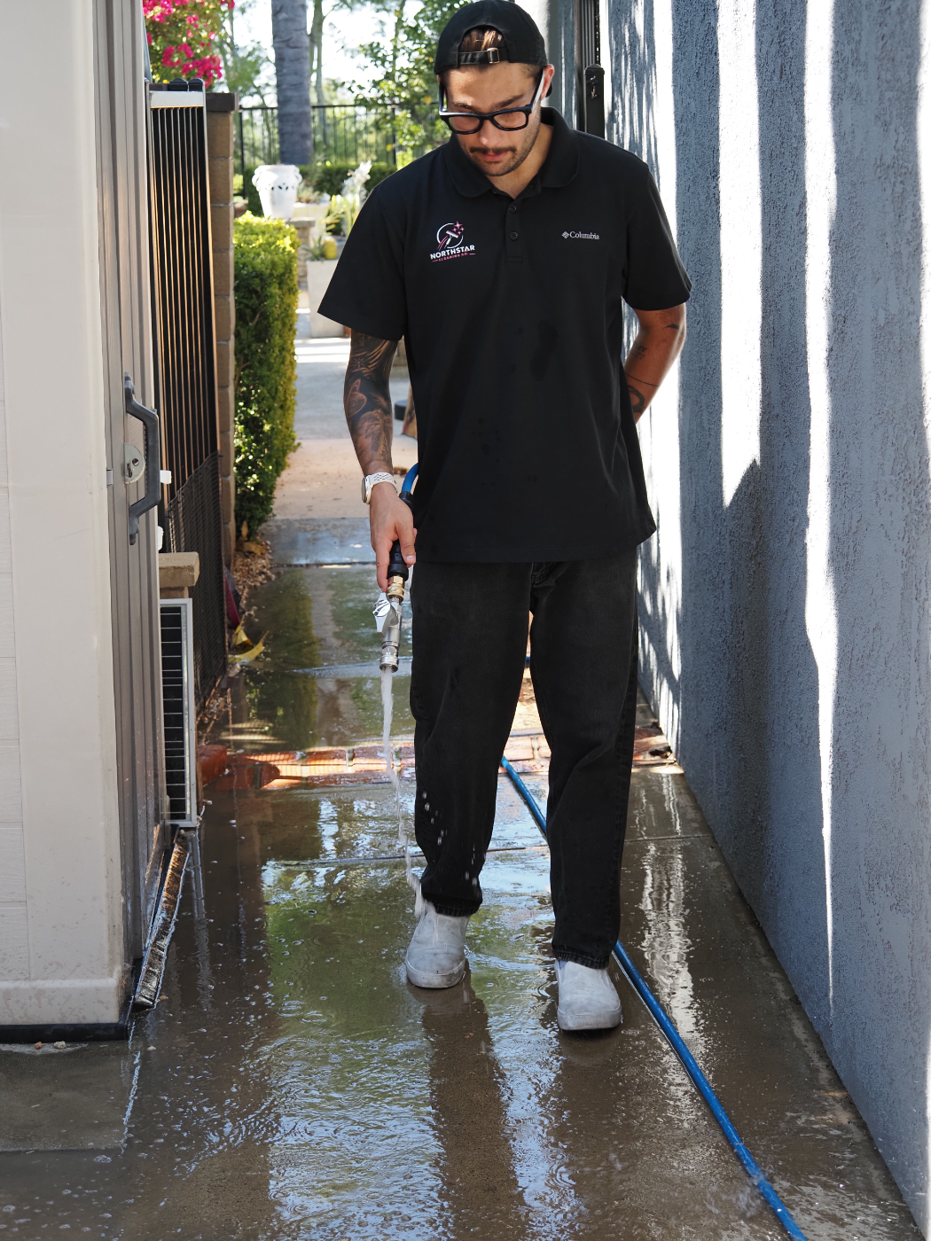 Dylan rinsing a side-yard walkway after the wash