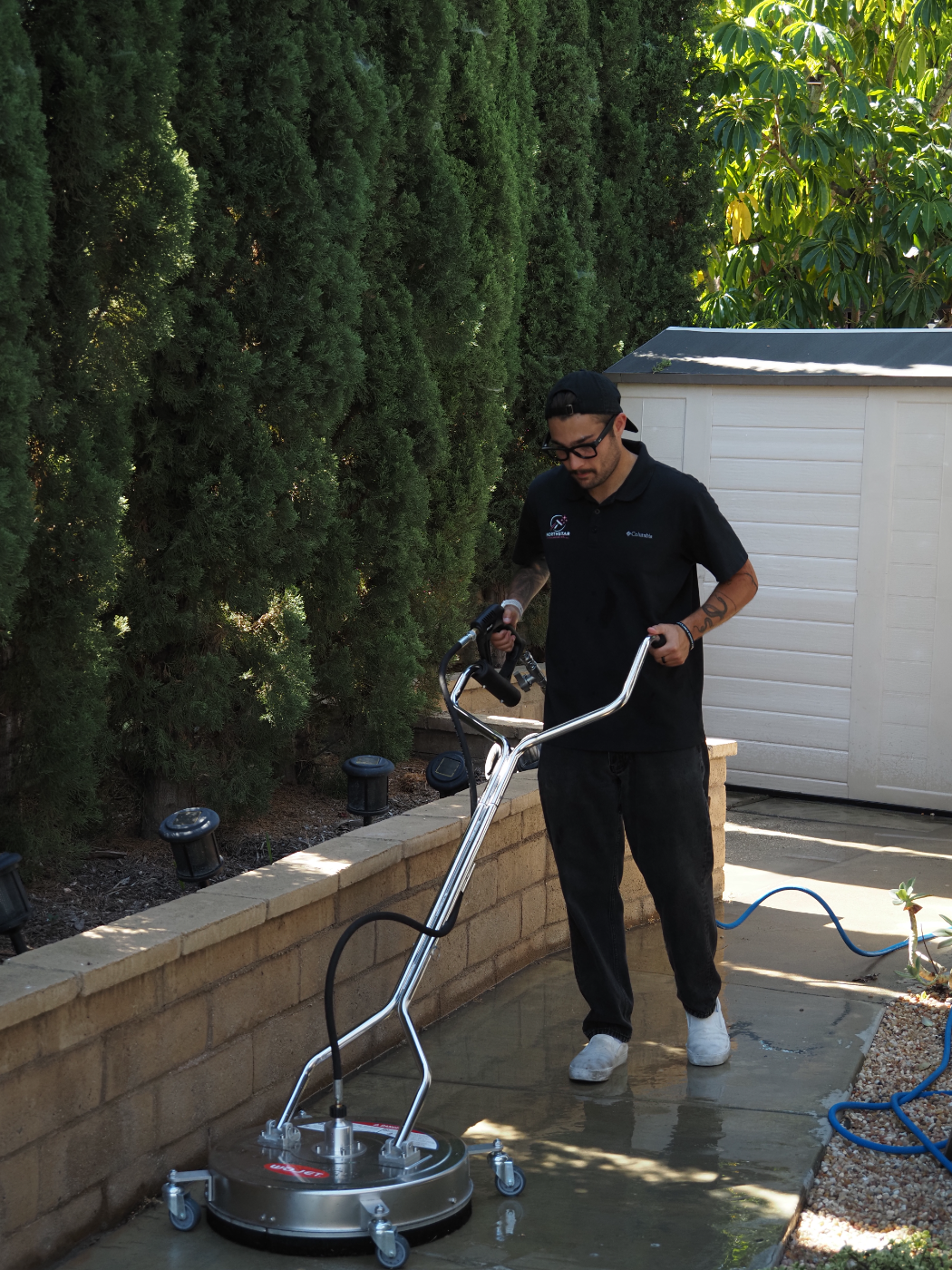 Dylan running a surface cleaner across a concrete patio